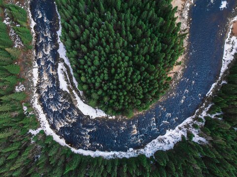 Aerial view of a river surrounded by trees and snow in Quebec, Canada