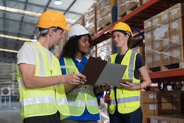 Male and female warehouse workers working checks stock and inventory and standing talking together at storage warehouse. Group of warehouse workers discuss and training work in distribution branch