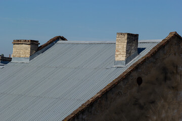 Roof of a new home. Ceramic chimney, metal roof tiles, gutters, roof window. Single family house