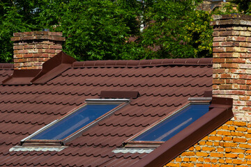 Red house roof with red brick chimney. Ceramic chimney, metal roof tiles, gutters