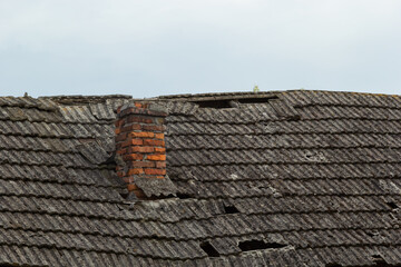 Fototapeta premium red brick chimney in the top of the village house. A roof made of tiles on the background of the sky
