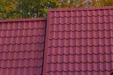 House with new brown metal tile roof and rain gutter. Metallic Guttering System, Guttering and Drainage Pipe Exterior