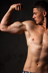 Fototapeta premium Athlete bodybuilder trains in the studio in the rain.