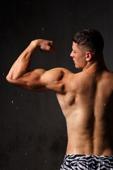 Athlete bodybuilder trains in the studio in the rain.
