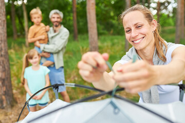 Woman setting up tent while camping with family