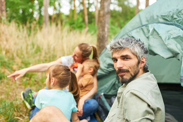Man sitting with family spending leisure time at campsite