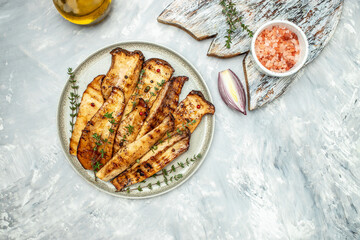 Slices of brown king oyster mushrooms, Pleurotus eryngii, cooked on grill with thyme on plate. Food recipe background. place for text, top view