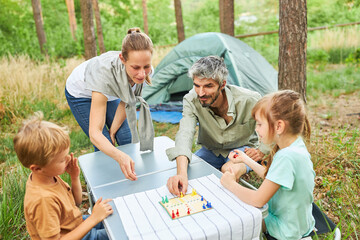 Family playing board game in forest during holiday