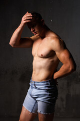 Fototapeta premium Athlete bodybuilder trains in the studio in the rain.