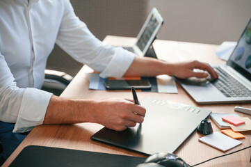 With graphic tablet. Close up view of designer's hands. Man in formal clothes is working in the modern office. Using computer