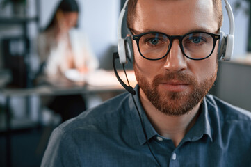 Portrait of man. Woman is on background. Two employees are working together in the modern office