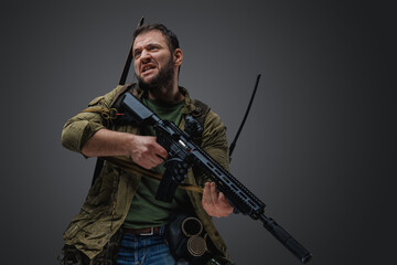 Studio shot of isolated on grey background aggressive man with rifle survived after armageddon.