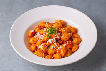 Traditional Italian food potato gnocchi with tomato sauce, parmesan cheese and fresh basil on dark table. Top view. Healthy food.