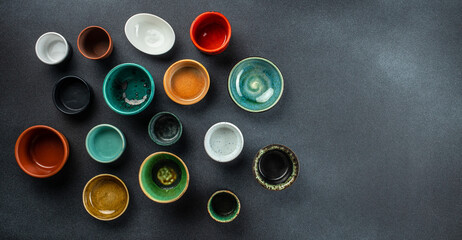 Collection of empty colorful ceramic bowls on a dark background. place for text, top view