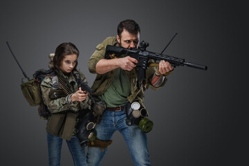 Fototapeta na wymiar Portrait of post apocalyptic girl teenager and guy with guns against grey background.