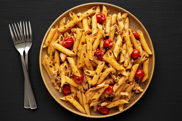 Homemade One-Pot Spinach and Tomato Pasta on a Plate on a black background, top view. Flat lay, overhead, from above.