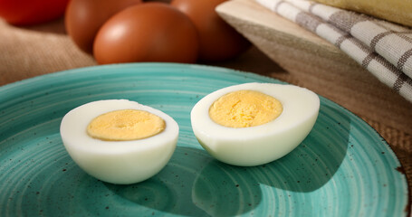 Halves of an egg on a plate. Boiled chicken eggs with bread and tomatoes. fresh eggs on the table. farm product closeup. natural healthy food. breakfast ingredients. rustic still life on a sunny day.