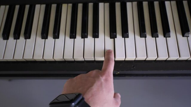 the shot of man's hand pressing piano keys, playing piano at house