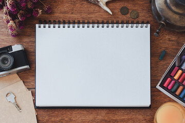 Notebook between various supplies and photo camera