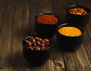Spices and herbs in ceramic bowls with stand on wooden table
