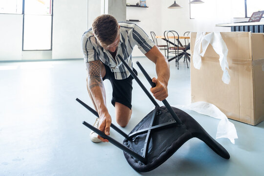 Young man assembling chair in home
