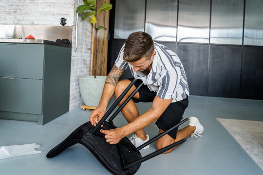 Young man assembling chair in home