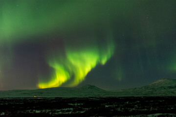 imagen de un paisaje nocturno nevado, con una aurora boreal en el cielo nocturno de Islandia 