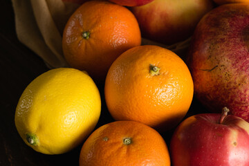 Fruit in a reusable bag. Earth day and zero waste concept. Apple, orange and pomegranate close-up on a dark background