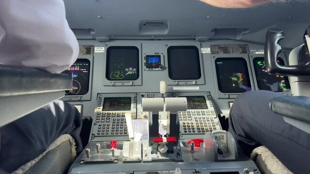 Interior view of a medium size jet during a real flight during the landing check. Copilot is flying. Captain lowers landing gear lever.