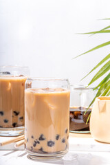 Iced tapioca coffee latte or boba pearl bubbles milk tea, asian trendy cold coffee drink with tapioca balls and crushed ice, on white marble background copy space