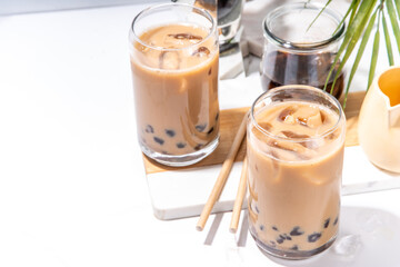 Iced tapioca coffee latte or boba pearl bubbles milk tea, asian trendy cold coffee drink with tapioca balls and crushed ice, on white marble background copy space