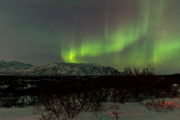 Fototapeta na wymiar imagen de un paisaje nocturno nevado, con montañas de fondo, y una aurora boreal sobre el cielo de Islandia 