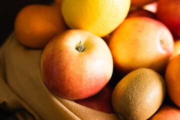 Fruit in a reusable bag. Earth day and zero waste concept. Orange, lemon, apple close-up, kiwi, pomegranate and wooden cutting board on dark background