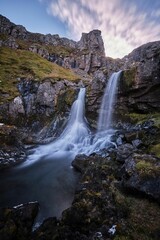 Obraz na płótnie Canvas Vertical long exposure shot of the Klifbrekku Waterfall in Iceland