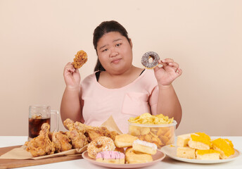 obesity young women binge eating disorder concept with woman eating fast food burger, fired chicken , donuts and desserts, junk food, high calorie foods, overweight female have unhealthy lifestyle.