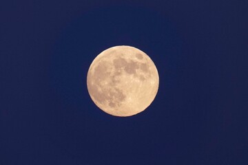Beautiful closeup of a magical full moon on a blue evening sky background