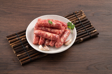 Raw Taiwanese sausage in garlic flavor in a plate on wooden table background.