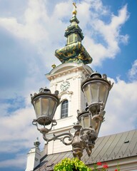 Fototapeta na wymiar Vertical low-angle view of vintage streetlights before an old church Clock tower