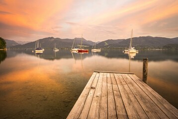 Jetty with sailing boats in the water at sunset.