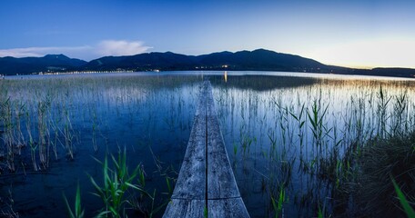 Narrow wooden pier in the lake against the mountains in the Alps