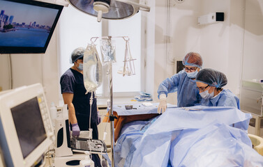 Surgeons operate on the legs of an elderly woman with varicose veins.