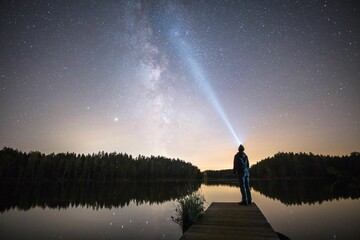 Wallpaper of a young boy enjoying the view of the Milky Way and the starry sky on a wooden pier