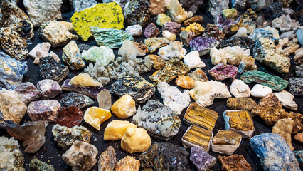 Multicolored Rough Gemstones, Top View. Big Collection of many Healing Crystals in a Gemstone Store. Vibrant Shiny Tiger Eye, Amethyst, Citrine, Smoky Quartz, Fuchsite, White Quartz Stones for Sale.