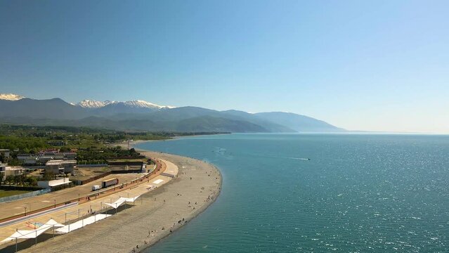 4k Aerial view of Adler, Sochi Beach, Town and Mountains. Waterfront Stretches Across the Coastline. Panoramic view of sea, mountains and city. 4k Aerial view of Adler, Sochi Beach, Town and Mountains