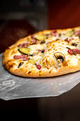 chef baker making pizza at kitchen. Put on landing shovel and send it to the oven.