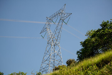 Torre de energia que passa cabos para região da cidade com fundo para paisagem.