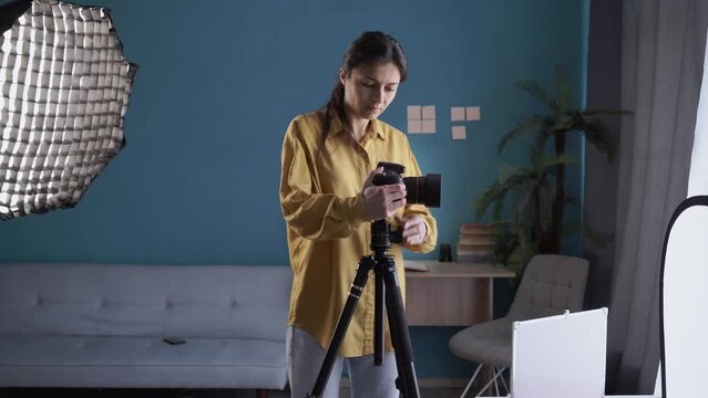 Tired woman photographer sitting rest with reflex camera in hands after work in home photo studio