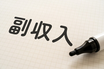 副収入と書かれたノートとマーカー