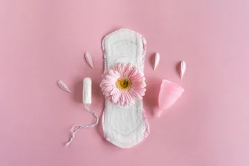 Zelfklevend Fotobehang Menstruation period concept. Hygienic white female pad, Menstrual cup and tampon with pink flowers. Menstruation, protection. Women's health © Анастасия Стягайло