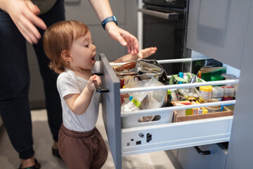 One year old child looking trough the kitchen drawer